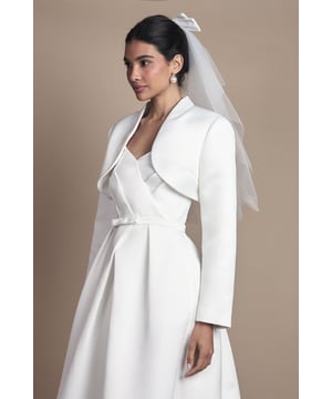 Elegant satin bolero jacket with distinctive curved collar design
        Cropped silhouette perfect for layering over bridal gowns
        Long sleeves with clean-lined finish for sophisticated coverage
        Structured shape that complements the natural waistline
        Versatile piece that can be worn throughout your wedding day celebrations
    
    This exquisite Coast bridal bolero jacket adds a touch of timeless sophistication to your wedding ensemble. The lustrous satin fabric creates a refined sheen that catches the light beautifully as you move through your special day. Designed with a graceful curved collar that frames the dcolletage, this jacket works harmoniously with strapless or sweetheart neckline gowns. The cropped length accentuates your waistline whilst providing elegant coverage for ceremony settings that may require more modest attire. Style with your bridal gown for the ceremony, then remove for a seamless transition to evening celebrations. This versatile piece can also be worn for pre-wedding events such as rehearsal dinners or post-wedding brunches, making it a treasured addition to your bridal wardrobe.