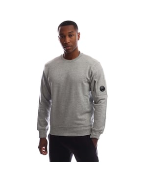 Mens C.P. Company Diagonal Raised Fleece Lens Crewneck Sweatshirt in greystone melange. Crew neck sweatshirt crafted in Diagonal Raised Fleece  a medium-weight brushed diagonal-weave cotton.  The soft fabric ensures comfort and ease of movement.  - Ribbed crew neck with logo detail at back neck.- Iconic C.P. Company lens detail pocket at left sleeve.- Ribbed cuffs and hem.- Regular fit.- 100% Cotton.  Machine washable.- Ref: RCCMSS713A 005086W M94