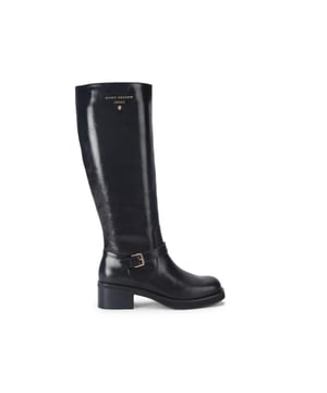 This Kurt Geiger Biker Knee Boot features a black leather upper with a simple buckled strap across the front of the boot. There is a gold tone branding detail on the outer side of the boot. Heel height: 5cm.