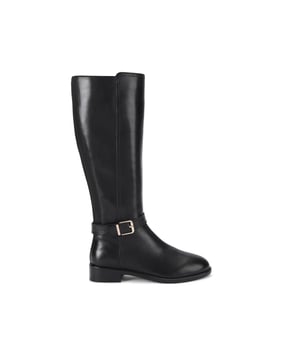 The Carvela Pienza Riding Boot is crafted from a smooth black leather. There is a gold buckle fastening the strap around the ankle.