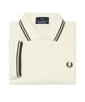 The Fred Perry Uniform Green Twin Tipped Collar Cream Polo Shirt combines timeless style with exceptional comfort. Crafted in England from 100% pure cotton, this polo features a soft cream body contrasted by a distinctive uniform green knit rib collar with matching twin tipping. Its classic design is perfect for elevating your casual wardrobe, offering breathability and durability for everyday wear. Whether dressing up or down, this iconic Fred Perry shirt delivers both quality and a polished look that stands the test of time. Experience the blend of heritage and modern appeal with a polo that truly defines effortless style