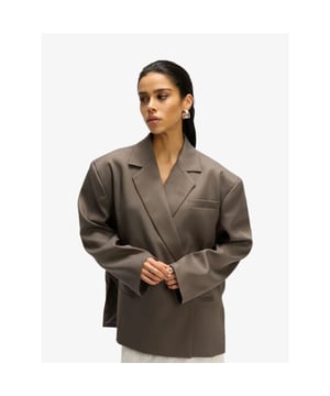 
Oversized blazer van een rijke kostuumstof. Ontworpen met een overslagmodel. Afgewerkt met een blinde knoopsluiting, paspelzakken, schoudervulling en een borstzakje. 

Als je de voorkeur geeft aan een meer normale pasvorm, raden wij je aan een maat kleiner te kopen