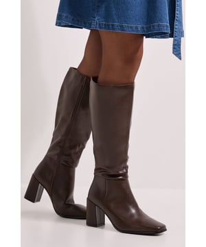 Sleek faux leather knee boots with a sophisticated square toe design
        Elegant high block heel measuring between 7-9cm for comfortable elevation
        Versatile knee-high length perfect for pairing with skirts and dresses
        Smooth silhouette with minimal detailing for timeless appeal
        Regular fit with subtle shaping that follows the natural contour of the leg
    
    These Kristen knee boots from Dorothy Perkins offer the perfect blend of style and practicality for your daywear wardrobe. The faux leather finish presents a polished appearance whilst the square toe adds a contemporary touch to this classic silhouette. Style these boots with a denim midi skirt as shown for a relaxed weekend brunch look, or pair with opaque tights and a knitted dress for autumn family gatherings. The substantial block heel provides stability without sacrificing height, making these boots comfortable enough for shopping trips or casual coffee dates. Their versatile design works beautifully with both fitted and flowing garments, allowing you to refresh multiple outfits in your collection with one stylish footwear choice. Perfect for the woman who appreciates on-trend details without compromising on comfort.