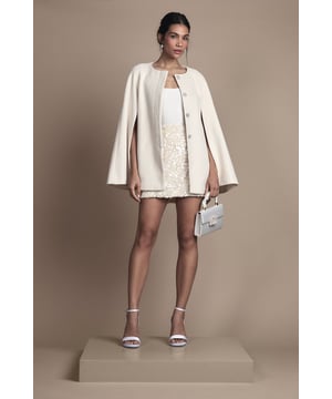Striking cape-style coat with elegant wide sleeves for a dramatic silhouette
        Collarless design with decorative jewelled buttons for sophisticated detailing
        Adjustable belt to cinch the waist and create a flattering shape
        Clean, minimalist lines perfect for formal occasions and special events
        Versatile length that pairs beautifully with both dresses and separates
    
    This captivating Belted Short Occasion Cape Coat from Coast offers a contemporary twist on formal outerwear. The distinctive cape silhouette creates a graceful drape that commands attention whilst maintaining an air of refinement. Style over an embellished mini dress as shown for wedding receptions or race day events, completing the ensemble with strappy heels and a structured handbag. The adjustable belt allows you to customise the fit according to your preference-wear loosely for a relaxed feel or cinched for a more defined waistline. The collarless neckline and ornate buttons add a touch of sophistication that transitions seamlessly from daytime ceremonies to evening celebrations. This coat is the perfect investment piece for the woman who appreciates timeless elegance with a modern sensibility.