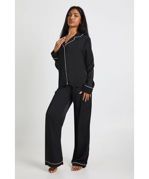 Luxurious satin pyjama set featuring elegant contrast piping detail along the edges
        Classic collared shirt design with full button-through front for timeless nightwear style
        Long sleeves with contrast piped cuffs for a sophisticated finishing touch
        Relaxed fit trousers with matching piping detail along the hem for a coordinated look
        Soft, smooth fabric with slight stretch for ultimate comfort during sleep
    
    Transform your nightwear collection with this sophisticated satin pyjama set from Boohoo. The contrast piping detail adds a touch of luxury to this classic design, whilst the smooth fabric gently drapes for a flattering silhouette. The long-sleeved shirt features a traditional collar and button-through front, perfect for lounging in style. Pair with fluffy slippers for cosy evenings at home, or throw on a soft dressing gown for extra warmth during chillier nights. The relaxed fit trousers offer unrestricted movement for a comfortable night's sleep, making this set ideal for both restful slumber and lazy weekend mornings. This versatile pyjama set strikes the perfect balance between comfort and style, ensuring you look as good as you feel when winding down after a long day.