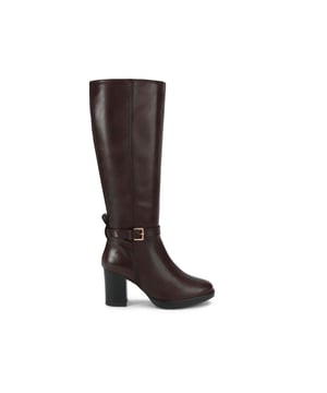 This KG Kurt Geiger Sage knee high boot is crafted from a rich dark brown leather. There is a strap around the ankle that is fastened with a gold buckle and a gold pin stud at the back. Heel height: 8cm.