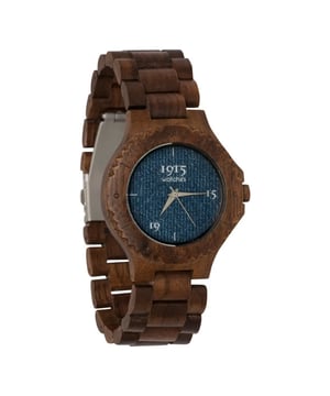 
De 1915 Watch Lady Denim is een verbluffend staaltje van creativiteit en vakmanschap, een horloge dat niet alleen de tijd weergeeft, maar ook een verhaal vertelt. Dit unieke dameshorloge combineert de robuuste charme van walnoothout met de ongeëvenaarde coolheid van denim, waardoor het een must-have is voor elke liefhebber van unieke modeaccessoires. Het horloge is vervaardigd uit walnoothout, bekend om zijn grove structuur en verweerde uitstraling. Deze keuze voor walnoothout geeft het horloge een stoer en natuurlijk karakter, vergelijkbaar met dat van gebruikt steigerhout, maar met het comfort en de elegantie die je van een kwaliteitshorloge verwacht. De echt unieke eigenschap van de 1915 Watch Lady Denim is echter de wijzerplaat, gemaakt van stoere denim stof. Deze ongebruikelijke maar stijlvolle keuze maakt het horloge een echte blikvanger en toont de durf en innovatie achter het ontwerp. De denim wijzerplaat vormt een prachtig contrast met het donkere walnoothout en voegt een eigentijds element toe aan het traditionele horlogedesign. De horlogekast heeft een diameter van 38mm, wat het een elegante maat geeft voor de vrouwelijke pols. De breedte van de horlogeband is 21mm, wat zorgt voor een gebalanceerde en comfortabele pasvorm. Bovendien kan de band eenvoudig worden aangepast door schakels te verwijderen, zodat het horloge perfect past bij elke drager. De 1915 Watch Lady Denim onderscheidt zich met een sportieve ring rond de wijzerplaat, wat het horloge een moderne en dynamische uitstraling geeft. Dit element benadrukt het sportieve karakter van het horloge en maakt het een veelzijdig accessoire dat zowel bij casual als formele gelegenheden gedragen kan worden. De 1915 Watch Lady Denim is meer dan een horloge; het is een uitdrukking van persoonlijke stijl, een samensmelting van traditie en moderne flair, en een hommage aan degenen die durven te kiezen voor het ongewone. Perfect voor de vrouw die houdt van de robuuste elegantie van hout en de tijdloze stijl van denim.