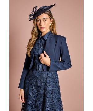 Elegant cropped jacket with sophisticated long sleeves and clean-lined silhouette         Striking bow detail at the back adds a feminine flourish         Collarless design with open front creates a sleek, contemporary profile         Crafted from crepe fabric with slight stretch for comfortable movement         Fully lined for smooth wear and structured appearance
    
    This beautifully tailored Coast jacket presents the perfect finishing touch for special occasions. The cropped silhouette sits elegantly at the waist, complementing dresses and separates alike, whilst the charming bow detail at the back offers an unexpected twist to a classic design. As shown, pair with a floral midi dress and fascinator for race day sophistication, or style with tailored trousers and a silk camisole for evening events. The clean lines and refined structure make this jacket a versatile investment piece that works brilliantly for weddings, formal gatherings and celebrations. The slight stretch in the fabric ensures comfort throughout the day, whilst maintaining that polished silhouette that Coast is renowned for. Accessorise with delicate jewellery to complete your occasion ensemble with understated elegance.