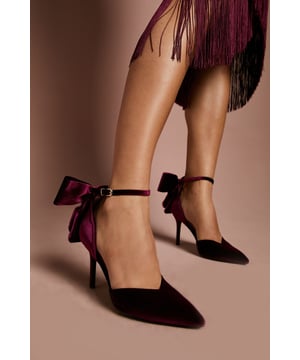 Luxurious velvet court shoes with a striking back bow detail
        Pointed toe silhouette for a sophisticated finish
        Elegant high stiletto heel measuring between 7-9cm
        Ankle strap with secure buckle fastening
        Leather upper for comfort and durability
    
    The Kittie court shoes from Coast showcase dramatic style with their sumptuous velvet texture and statement back bow. These head-turning heels feature a classic pointed toe and slender stiletto heel that creates a graceful silhouette. Perfect for formal occasions, pair them with a tailored midi dress or an elegant jumpsuit for weddings and race day events. The ankle strap provides security while adding a feminine touch to your ensemble. For evening affairs, style with a sleek cocktail dress and minimal jewellery to let these shoes command attention. The versatile design works beautifully with both contemporary and traditional outfits, making them a wardrobe essential for any special occasion where you wish to convey refined glamour and sophistication.