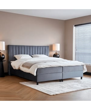 
Boxspring met opbergruimte Wanda Grijs De Boxspring met opbergruimte Wanda Grijs biedt niet alleen een luxueuze slaapervaring, maar ook een slimme oplossing voor het organiseren van je slaapkamer. Deze stijlvolle boxspring, met een zachte grijze stof, combineert elegantie met functionaliteit, waardoor je slaapkamer zowel opgeruimd als aantrekkelijk blijft. Het hoofdbord heeft dezelfde breedte als het bed en is circa 118 cm hoog. Dit geeft een luxueuze uitstraling en biedt stevige ondersteuning tijdens het zitten of lezen in bed. Met een hoogte van 23 cm zorgt het matras, voorzien van pocketvering en HR-koudschuim afdeklaag, voor uitstekende drukverdeling en comfort. Het houten boxspringframe van 21 cm hoog biedt extra stabiliteit en duurzaamheid. De ruime opbergruimtes onder het bed zijn eenvoudig toegankelijk via beide zijden. Dankzij deze praktische opbergmogelijkheden kun je spullen zoals extra lakens, winterkleding of decoratieve kussens gemakkelijk opruimen. De poten van 12 cmSpecificatiesinclusief Pocketvering Hybride Matras 23 cmMateriaal: HoutKleur: GrijsAfmetingen: 180x200 cm