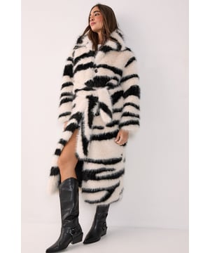 Striking zebra print faux fur texture for a bold statement look
        Longline silhouette with a flattering belted waist
        Sophisticated collared neckline adding structure to the design
        Front button fastening for versatile styling options
        Cosy yet fashion-forward design perfect for making an entrance
    
    Make a dramatic entrance in this head-turning zebra print faux fur coat from NastyGal. The longline silhouette creates a luxurious feel whilst the belted waist allows you to customise the fit to your preference, creating a flattering silhouette. This standout piece transitions effortlessly from day to night - pair with casual denim and knee-high boots for daytime drama, or throw over a sleek evening dress for a night out. The collared neckline adds a touch of sophistication to the bold pattern, making it suitable for both casual and more formal settings. During colder months, this coat provides both warmth and style, proving that practical outerwear needn't compromise on fashion credentials. A true wardrobe hero that will turn heads season after season.