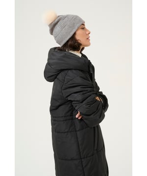 Gebreide beanie met zachte textuur, brede geribde rand en een pluizige pompon bovenop. Sluit nauw aan, straalt nonchalance uit.