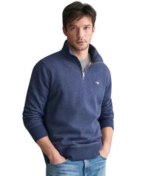 Dieses vielseitige Sweatshirt mit halbem Reißverschluss vereint Komfort und Stil mit einem hochwertigen Mischgewebe aus Baumwolle und Polyester, das perfekt für Übergangswetter geeignet ist. Mit einem kleinen, kunstvoll gestickten GANT-Logo auf der Brust präsentiert es ein dezentes, aber elegantes Design. Der gerippte Saum und die Bündchen kreieren eine maßgeschneiderte Silhouette. Entworfen für eine reguläre Passform, verleiht der halbe Reißverschluss einen Hauch sportlicher Eleganz, während der strapazierfähige Stoff für langfristigen Tragekomfort sorgt. (GANT_SWT_2008005)