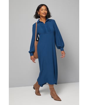 Elegant pintuck detailing on the front bodice adds sophisticated texture
        Flattering trapeze silhouette that gracefully skims the body
        Classic collared neckline with partial button placket for refined styling
        Voluminous balloon sleeves with fitted cuffs create a dramatic silhouette
        Midi length design offers versatile styling options for various occasions
    
    This Wallis woven shirt dress combines comfort with sophistication through its relaxed trapeze silhouette and thoughtful design details. The pintuck front adds subtle texture while the collared neckline maintains a polished appearance. Style with ankle boots for a casual daytime look that transitions effortlessly from family gatherings to weekend brunches. The balloon sleeves add a contemporary touch to this otherwise classic piece, making it perfect for those who appreciate both comfort and style. Layer with a tailored blazer and accessorise with simple jewellery for more refined daywear occasions. The versatile midi length works beautifully with both flats and low heels, making this an adaptable addition to your wardrobe that can be styled differently throughout the seasons.