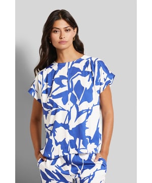 Een blouse die opvalt door de zomerse bloemenprint en een individuele en moderne touch krijgt door de verlaagde schouders en ronde halslijn. De blouse is gemaakt van een zacht en vloeiend materiaal.
