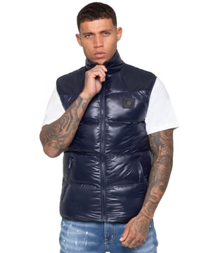 Elevate your outerwear with the Enzo Milano Men’s Puffer Gilet, designed for both style and practicality. Featuring an embroidered Enzo Milano logo on the zip guard and a sleek metal badge on the chest, this gilet delivers a touch of luxury. Built with functionality in mind, it includes two secure side zip pockets and a single inside zip pocket to keep your essentials safe. The drawcord hem with an adjustable toggle ensures a personalised fit, while the shiny finish gives it a modern, standout look.
