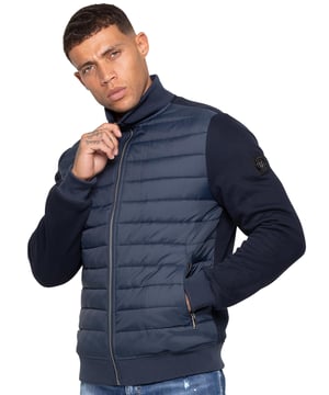 Step up your outerwear with the Enzo Milano Men’s Hybrid Jacket. Featuring a ribbed funnel neck collar and a padded, water-resistant poly front panel. The cotton jersey back panel and sleeves ensure flexibility and breathability, while ribbed cuffs and hem create a secure fit. Practical details include two side zipped pockets and inside storage options. Finished with the signature Enzo Milano metal badge on the left arm.