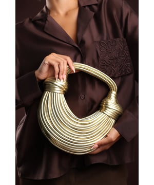 The Blossom Curved Metallic Shoulder Bag is a bold statement piece with a sculpted silhouette that adds instant glamour to any outfit. Crafted from faux leather with a radiant metallic finish, it features a distinctive curved design and structured handle detail that make it stand out from the crowd. Compact yet functional, it offers enough space for evening essentials while remaining lightweight and stylish. Perfect for parties, special occasions, or when you want your accessories to make an impact. Key Features: • Material: Faux leather with metallic finish • Dimensions: Compact curved shape for essentials • Fastening: Secure top closure • Detail: Sculpted curved design with structured handle for statement style