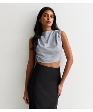 Verwen jezelf met luxe met onze Silver High Neck Sleeveless Satin Top. Deze top is gemaakt van glad, glinsterend satijn en heeft een elegante hoge hals en een mouwloos ontwerp. Een perfecte keuze voor elke geraffineerde en exclusieve gelegenheid. Verhoog je garderobe met dit tijdloze stuk.
