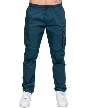 Upgrade your everyday style with the Enzo Men's Cargo Pants. Crafted from premium stretch fabric, these lightweight trousers offer a tapered leg fit for a sleek, modern look. Featuring an elasticated waistband with an adjustable toggle, they provide a customizable fit, while the adjustable toggle ankles let you tailor the look and feel. With two side slash pockets, two cargo pockets with secure Velcro fastening, and a single back welt pocket, you’ll have ample storage for essentials. Finished with an Enzo print on the cargo pocket. (649)