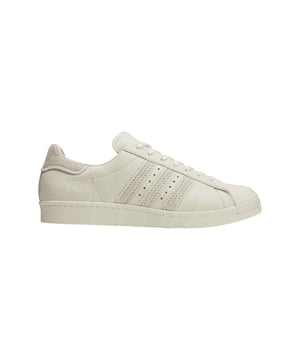 Y-3 Superstar Trainers in gebroken wit. De iconische Superstar schoenen zijn ongetwijfeld een van de meest gevierde sneakers van adidas en krijgen een update van Y-3. Ze zijn gemaakt van eersteklas leer en suède. Met een knipoog naar de Japanse techniek van Sashiko stiksels hebben de sneakers geaccentueerde en ton-sur-ton stiksels rond de eyestay hiel tab tussenzool en de kenmerkende 3-Stripes met alle draden opzettelijk losjes hangend. De klassieke rubberen kuipneus valt nog meer op met dik borduursel op de plek waar normaal de originele lijnen zitten.- Y-3's interpretatie van de adidas Superstar schoenen geïnspireerd op traditionele Sashiko stiksels. - Vetersluiting.- Bovenwerk van leer en suède.- Voering van leer en canvas.- Geborduurde rubberen neus.- Y-3 logo.- Rubberen loopzool.- Bovenwerk van leer en suède Voering van leer en textiel Synthetische zool.- Ref: ID4122