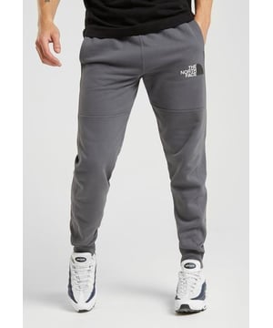 The North Face Herren M COT Pant Graue Jogginghose. Abgerundet mit dem The North Face-Branding am linken Oberschenkel und an der Rückseite des Beins. Elastischer Bund mit Kordelzug. 2 seitliche Eingrifftaschen. Das Model trägt Größe M.