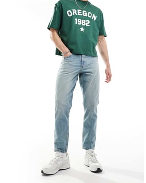 ASOS DESIGN tapered fit jeans med vintagefärg i ljusblå tvätt