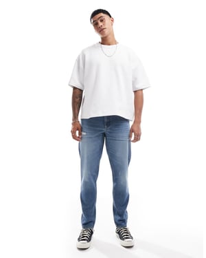 ASOS DESIGN tapered jeans med slitage i mellanmörk blå
