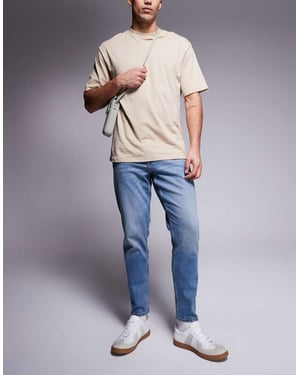 ASOS DSIGN stretch tapered jeans i mellan tvätt med vintageskugga