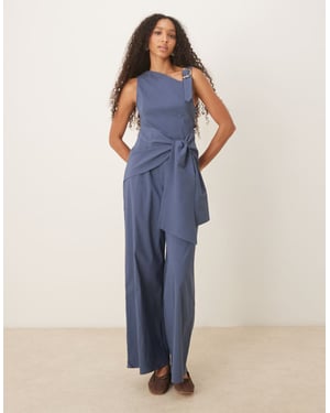 ASOS DESIGN asymmetrisk jumpsuit i flytande guld med banddetalj och omslag i marinblått