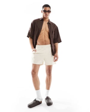 ASOS DESIGN swim shorts in short length in beige