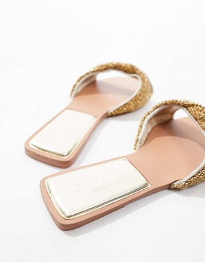 Simmi London Kenya – Guldfärgade platta sandaler med utsmyckade remmar
