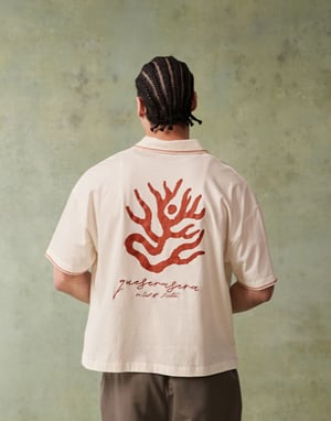 ASOS DESIGN boxig kortärmad polo med brodyr på bröstet och grafik på ryggen i off white