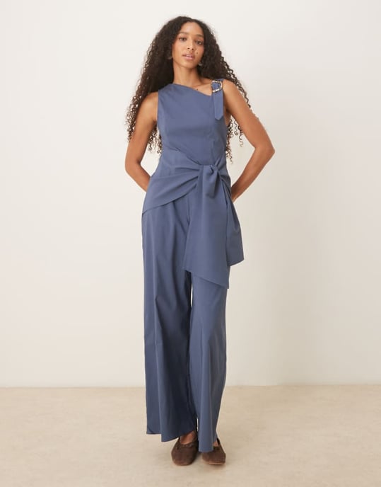 ASOS DESIGN asymmetrisk jumpsuit i flytande guld med banddetalj och omslag i marinblått - Image 1