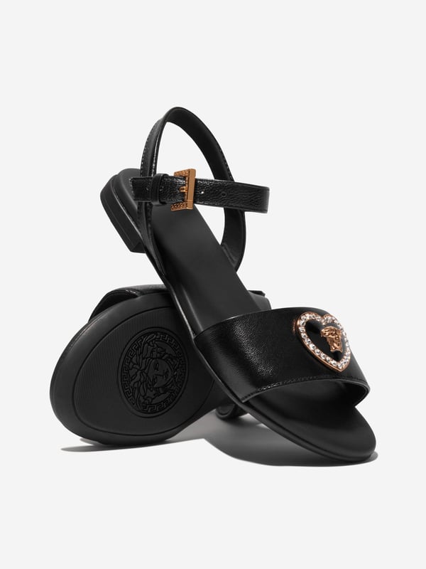 Introducing the Versace Girls Leather Heart Logo Sandals in Black, an opulent blend of Italian craftmanship and fashionable utility, perfect for holiday ensembles. Key highlights include: Italian-made: Born from the masterful techniques of Italian artisanship, rendering it durable and timelessly elegant. Heart Logo Accent: Elevate your child's style quotient with the iconic Versace heart logo, making these sandals a true statement piece. Supreme Comfort: Fabricated from premium leather ensuring comfort and ease, accompanying your child's every step.Transform the Holiday wardrobe! With these Versace Girls Leather Heart Logo Sandals in Black. Shop now for a taste of luxury for your little fashionista!