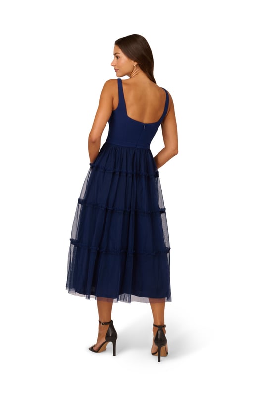 Modern fabric mixes make this classic fit and flare dress a sweet look. This midi dress features a fitted bodice with tank straps, a square neckline, and a tiered skirt. Fully lined, the bodice is crafted from a knit fabrication while the skirt is overlaid in mesh for added sweep. Pockets and a square back with centre zip closure complete this delightful party dress. Styled with nude heels and sparkling accessories, this midi dress is a timeless look from wedding guest duty to cocktail parties