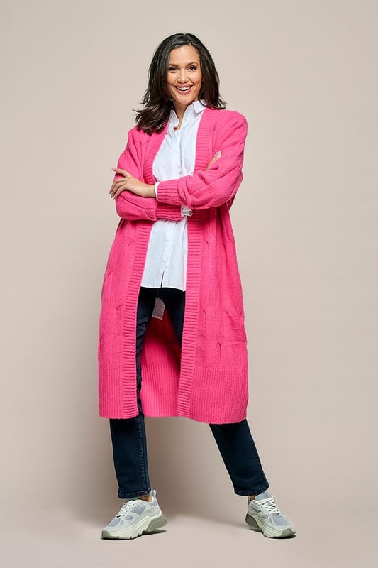 Het Chelsea kabelvest in een zachte roze kleur is een prachtig gebreid, lang vest met een openvallend ontwerp en robuuste ribboorden. Met een relaxte pasvorm die net boven de kuit valt, biedt dit vest een comfortabele en elegante uitstraling. Een afneembaar strikceintuur voegt een vleugje tailleaccentuering toe aan het geheel. Vervaardigd uit een wolmix van 47% acryl, 22% nylon, 20% wol, 8% alpaca en 3% spandex, biedt dit vest warmte en comfort, waardoor het ideaal is voor koude winterdagen. De combinatie van wol en alpaca verleent het vest een zachte en luxueuze textuur, terwijl acryl en nylon zorgen voor duurzaamheid en vormbehoud. De toevoeging van 3% spandex biedt een lichte stretch, wat resulteert in een comfortabele en flexibele pasvorm.Kortom, het lange roze Chelsea vest is een stijlvol en veelzijdig kledingstuk, met zijn losse snit, bijbehorende strikceintuur en prachtig gebreide ontwerp. De combinatie van diverse hoogwaardige materialen garandeert zowel comfort als stijl, waardoor het een uitstekende aanvulling is op je wintergarderobe. Het Chelsea vest biedt talloze mogelijkheden om verschillende stijlvolle en comfortabele outfits te creëren.Een suggestie is om het Chelsea vest te dragen over de Jesper travel top, samen met de Indy travel broek in een opvallende kobaltkleur. Het contrasterende kobaltblauw voegt een levendige dimensie toe aan het roze vest, wat zorgt voor een sprankelende outfit. Je kunt ook het Chelsea lange vest combineren met de Cassidy tuniek in een veelkleurig patroon, samen met de zwarte legging. Het levendige en kleurrijke patroon van de tuniek creëert een boeiend contrast met het effen roze vest. Eveneens kun je het roze kabelvest succesvol combineren met de Audrey print blouse. Onthoud dat jouw comfort en zelfverzekerdheid in je kledingkeuze centraal staan. De combinatie van de roze tint en het sprankelende, veelkleurige patroon geeft je outfit een krachtige en vrolijke uitstraling.