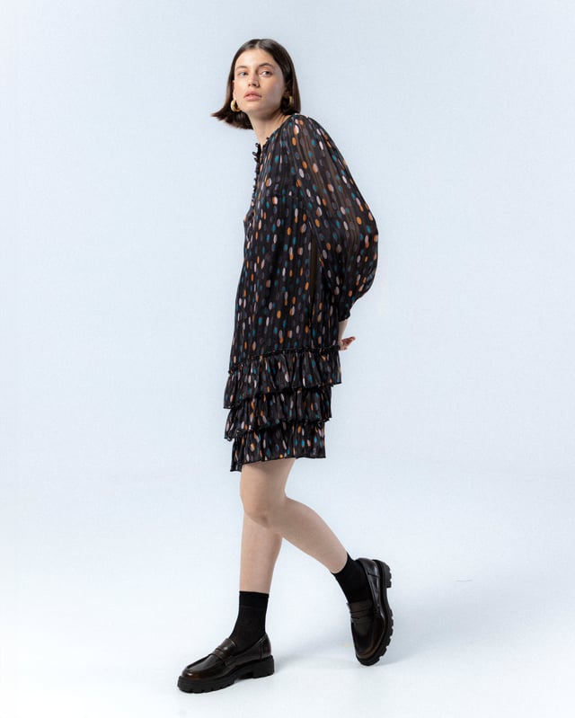 El vestido de lunares Alejandra, con su encantador estampado de lunares en tonos cálidos sobre fondo oscuro, te hará sentir la magia del otoño. Su diseño elegante y favorecedor es ideal para cualquier evento, añadiendo un toque de sofisticación y alegría a tu look.
 
 
 
 Vestido corto. 
 
 Abertura en escote con cierre de botones hasta la cintura. 
 
 Botones con aplique de piedras a mano. 
 
 Manga larga con puño elástico. 
 
 Bajo de tres volantes. 
 
 Tejido viscosa. 
 
 Estampado lunares.