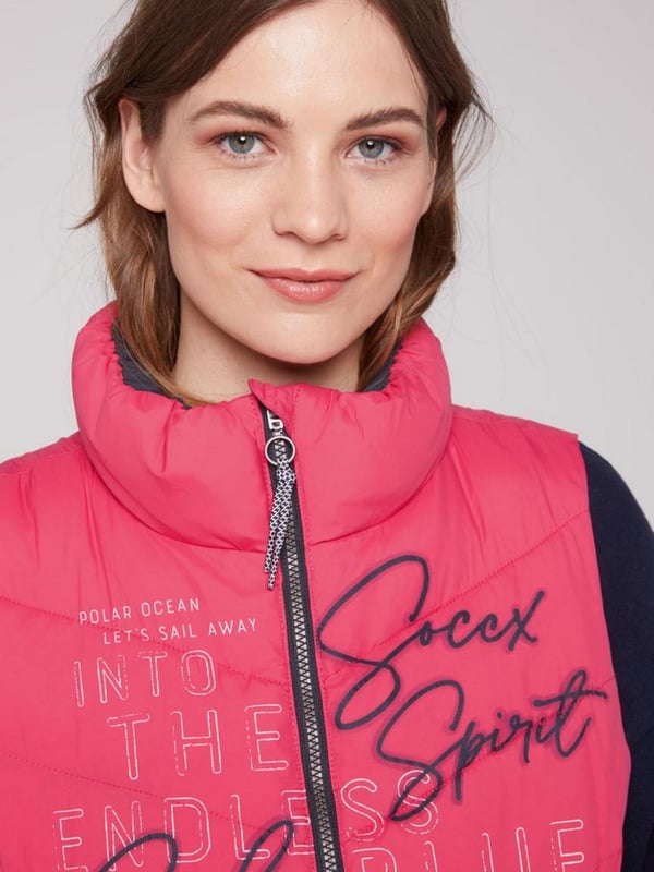 Ein schmückender Logo Print ziert die Vorderseite der Steppweste von SOCCX für Damen. Ein kleiner Print findet sich zudem auf dem oberen Rücken. Die Weste hat einen schön leichten Griff, Kontraststreifen an den Seiten und einen elastischen Abschluss am Saum. Und sie ist mit praktischen Reißverschlusstaschen ausgestattet. Sehr angenehm zu tragen, bequem und sportlich zugleich geschnitten. Lässt sich mit vielen Kleidungsstücken kombinieren.