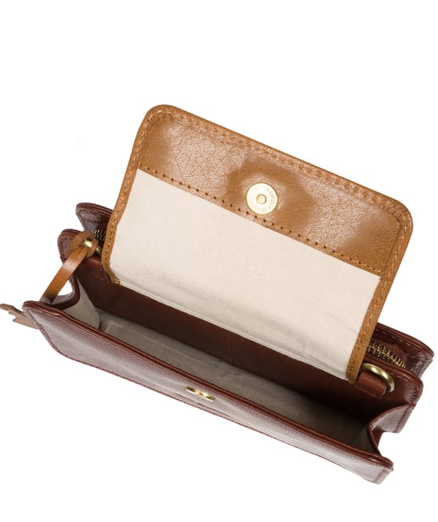The 'Little Wonder' cross body clutch bag from Conkca London is handcrafted from multi-toned leather for a beautiful finish. A magnetic press-stud secured cover opens to reveal a compartment ideal for a smartphone. A zip-over top opens to reveal a second compartment that is perfect for your essential items and has three handy card slots. Lined with natural and untreated 100% cotton. It comes with an adjustable leather strap with a maximum drop length of 68cm, which is removable, converting the bag into a clutch bag. Adorned with the inimitable Conkca squirrel charm and Conkca logos.