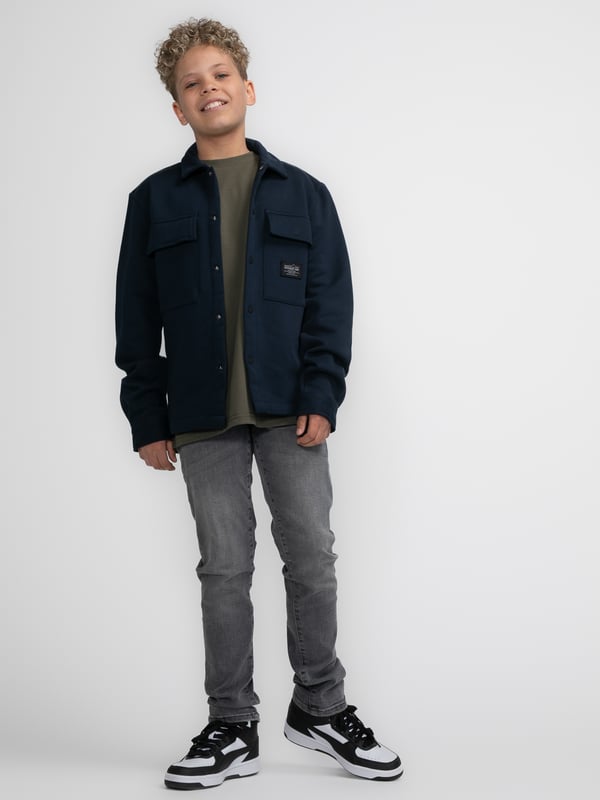 Overshirt aus Sweatstoff mit langen Ärmeln. Dieses Hemd verfügt über einen klassischen Kragen, einen Druckknopfverschluss, zwei Brusttaschen mit Druckknopfverschluss und ein Emblem auf einer Brusttasche. Das Overshirt ist mit Druckknöpfen an den Ärmeln versehen. Haben Sie Schwierigkeiten, sich zwischen zwei Größen zu entscheiden? Dann wählen Sie die größere Größe. Sweatstoff, klassischer Kragen, Druckknopfverschluss, zwei Brusttaschen, 100 % Baumwolle.