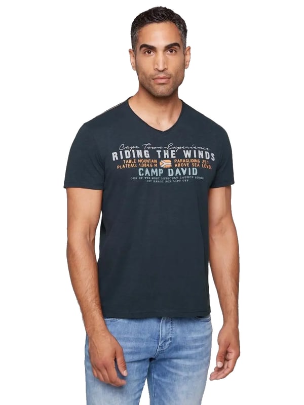 Dieses Herren-T-Shirt vereint lässigen Stil mit raffinierter Detailverliebtheit. Der V-Ausschnitt mit Used-Kante verleiht dem Shirt einen coolen, entspannten Look. Die Flammgarnstruktur sorgt für eine einzigartige Textur und unterstreicht die Individualität des Designs. Kontrastnähte an den Schultern setzen subtile Akzente, die das Gesamtbild perfekt abrunden. Ein markanter Front-Print mit Flockprint-Details zieht alle Blicke auf sich, während ein kleiner Logo-Print hinten und ein Label-Patch am linken Ärmel dezente Markenakzente setzen. Das Necktape sorgt für zusätzlichen Tragekomfort und Stabilität. Mit seiner normalen Passform und dem hohen Tragekomfort ist dieses Shirt ein Must-have für jeden Kleiderschrank. Ideal für lässige Outfits, die dennoch Stilbewusstsein ausstrahlen. Ein zeitloses Stück, das in keiner Garderobe fehlen sollte.
