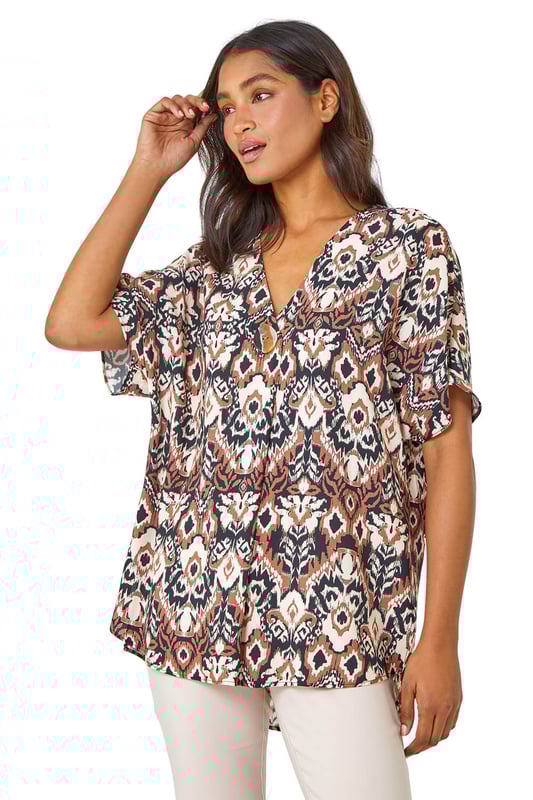 Button Detail Aztec Print Top from Roman. Step into the Summer with neutral prints and relaxed silhouettes. This overshirt has a bold statement button at the front, a feminine v-neckline and short batwing sleeves. It’s designed from a loose woven material for a comfortable and breezy everyday fit. Pair this ikat printed tee with a pair of cropped trousers and wedges for a stylish casual Spring Summer look.