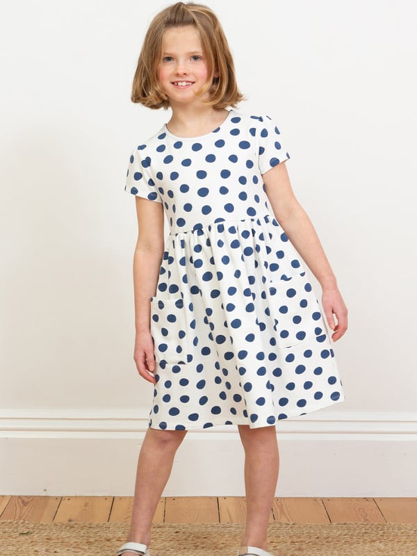 95% organic cotton 5% elastane | Proud to be certified to the Global Organic Textile Standard (GOTS) | Big spot all-over print | Cream and navy blue | French terry loop back fabric (240-250 gsm) | Coconut button shoulder opening (up to and including size 3 years) | Patch pockets | Short sleeved | Round neck | Made in Turkey | Machine washable at 40 degrees, or at 30 degrees to be kinder to the planet