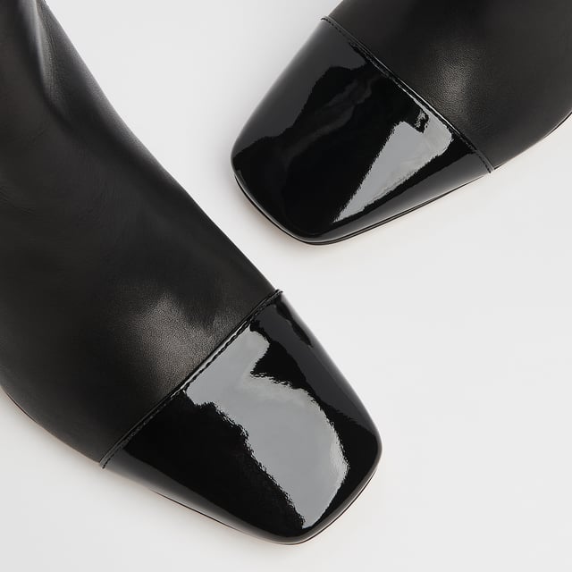 LK Bennett Bess Knee Boots, Black A classic knee boot with a difference, our Bess boots take on the season's toe cap trend. Crafted in Italy from beautifully-soft black calf leather, they have a square toe with a black patent toe cap, seam detail to the front, an inside zip and a leather-covered squared block heel. They're perfect with Sixties-inspired mini dresses and Seventies-style midi dresses.