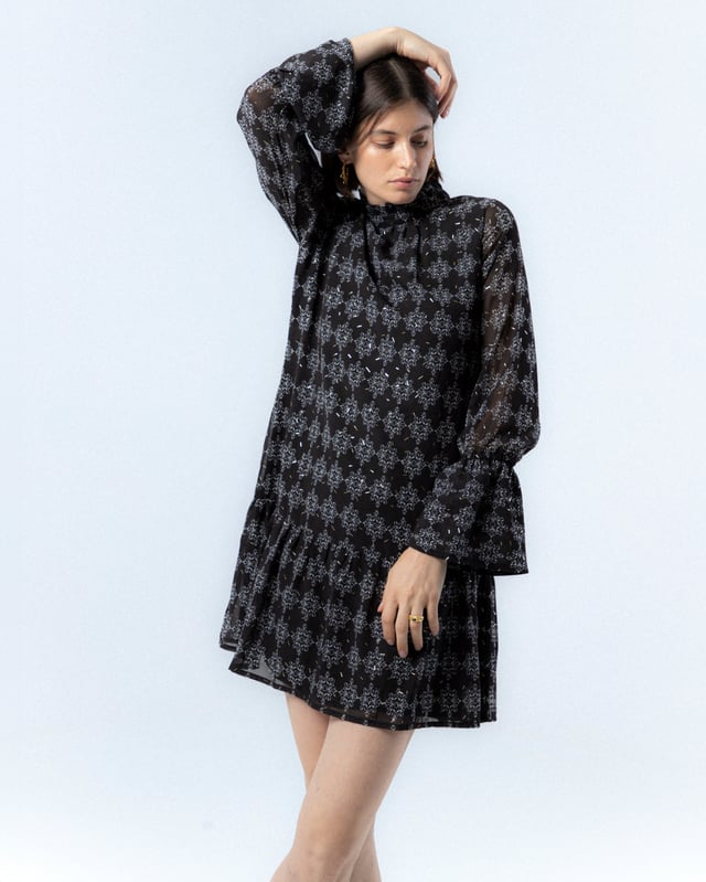 El vestido con volante Catalina en azul te hará sentir la frescura del invierno. Con su diseño elegante y detalles de volantes, esta prenda añade un toque de sofisticación y movimiento a tu look. Perfecto para cualquier ocasión, realza tu silueta con su lazada en la cintura.
 
 
 
 Vestido corto con cuello redondo. 
 
 Manga larga con puño elastico y volante a la altura del codo. 
 
 Cierre en espalda con cremallera. 
 
 Tejido estampado geométrico con detalles de foil dorado.
