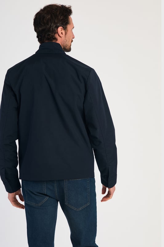 This Harrington Style Jacket by Kensington Eastside features a button-up collar, pop button sleeves, and a durable PVC coating. The checked mesh inner lining enhances comfort, while two side pockets and an embroidered logo add style and functionality, making it a perfect choice for casual wear.