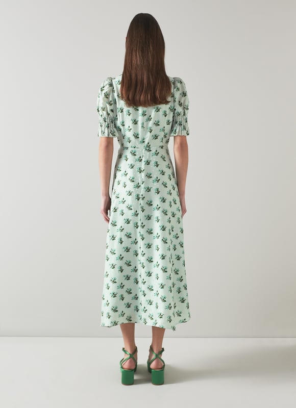 The Tabitha dress is crafted from a silk-blend spot jacquard in morning mist green with a 1930's hand painted primula print reimagined from vintage archives. It has a round neck, puff shoulders, short shirred sleeves, pleating at the bust, a floaty shape and a dipped midi-length hem.