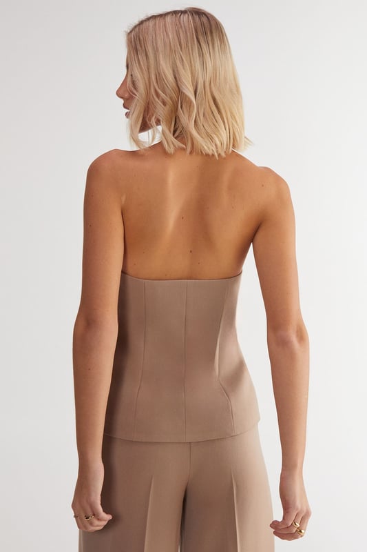 Sleek tailored vest with button front closure
        Plunging V-neckline for a sophisticated look
        Halter-style design with open back
        Single decorative button detail at the waist
        Versatile piece for layering or wearing alone
    
    Elevate your workwear wardrobe with this chic tailored vest from NastyGal's Essentials collection. Perfect for the modern professional, this sleek piece offers a contemporary twist on classic office attire. Style it over a crisp white shirt and pair with tailored trousers for a polished look that commands attention in the boardroom. For a more relaxed yet refined ensemble, layer it over a lightweight turtleneck and team with high-waisted wide-leg trousers. The vest's versatility shines through as day turns to night - simply pair it with sleek cigarette trousers and statement earrings for after-work drinks. With its ability to transition seamlessly from desk to dinner, this tailored vest is a must-have addition to any fashion-forward professional's wardrobe.