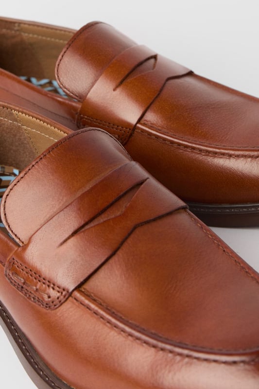 Classic penny loafer design with a modern twist
        Smooth leather upper for a polished appearance
        Slip-on style for easy wear
        Sturdy sole with a slight heel for comfort
        Versatile tan colour suitable for various outfits
    
    Step into sophistication with these smart penny loafers from Maine. The timeless design is given a contemporary update, perfect for the modern gentleman who appreciates classic style. These versatile shoes effortlessly bridge the gap between smart and casual, making them an ideal choice for a range of occasions. Pair them with tailored trousers and a crisp shirt for a refined office look, or dress them down with chinos and a polo shirt for smart-casual events. The slip-on style ensures convenience, while the durable sole provides all-day comfort. Whether you're attending a business meeting or enjoying a weekend brunch, these loafers will add a touch of elegance to your ensemble. Their ability to complement both formal and relaxed attire makes them a must-have addition to any discerning wardrobe.